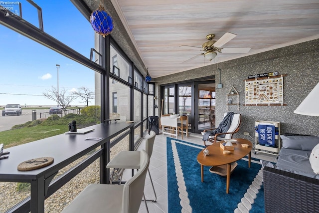 sunroom with a ceiling fan and tile patterned floors