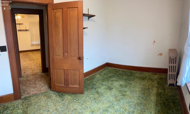 unfurnished bedroom featuring baseboards, radiator, and carpet