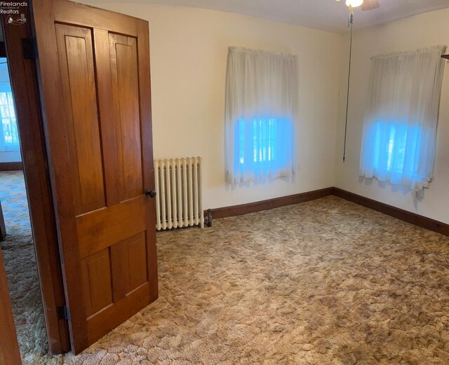 unfurnished bedroom with a closet, baseboards, radiator, and carpet floors