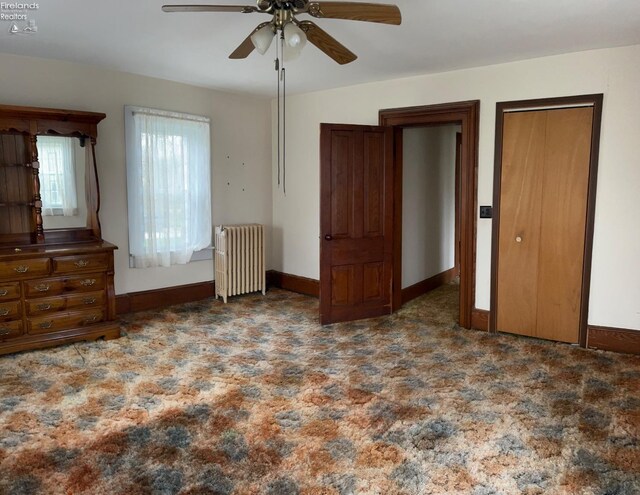 unfurnished bedroom featuring radiator heating unit, carpet flooring, baseboards, and ceiling fan