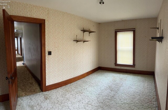carpeted spare room featuring baseboards