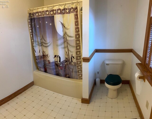 bathroom with toilet, tile patterned floors, shower / bath combo with shower curtain, and baseboards