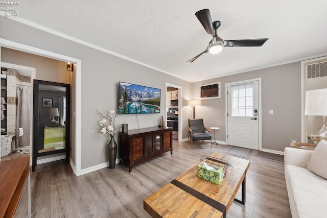 living area with ornamental molding, light wood finished floors, baseboards, and a ceiling fan