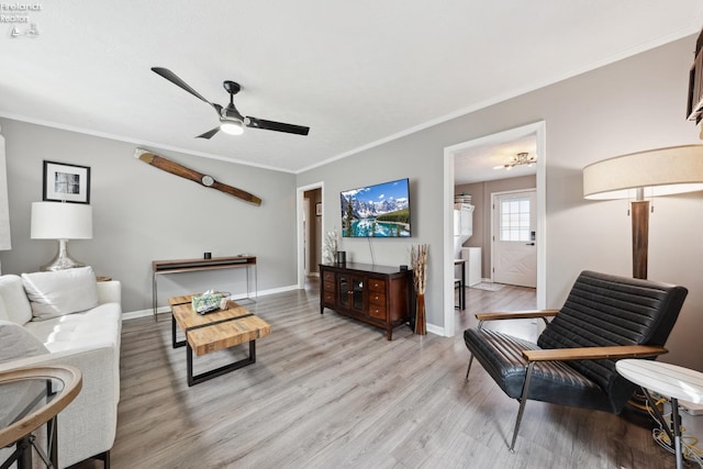 living room with ornamental molding, baseboards, light wood-type flooring, and a ceiling fan