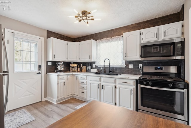 kitchen with white cabinets, a sink, backsplash, and appliances with stainless steel finishes