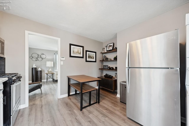 kitchen featuring light wood-type flooring, appliances with stainless steel finishes, and baseboards