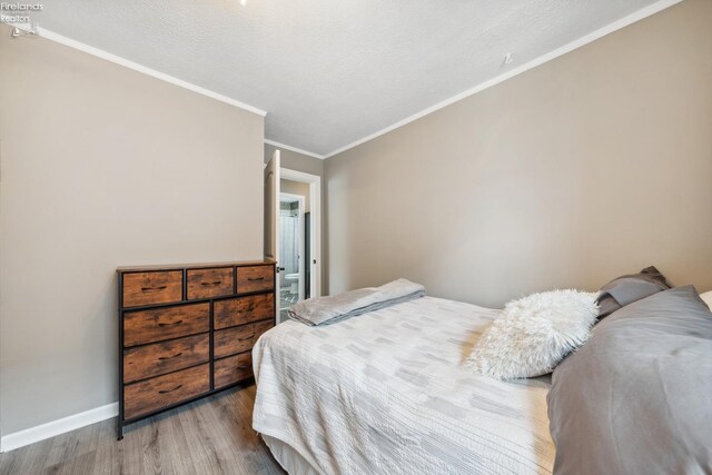 bedroom with wood finished floors, baseboards, and ornamental molding