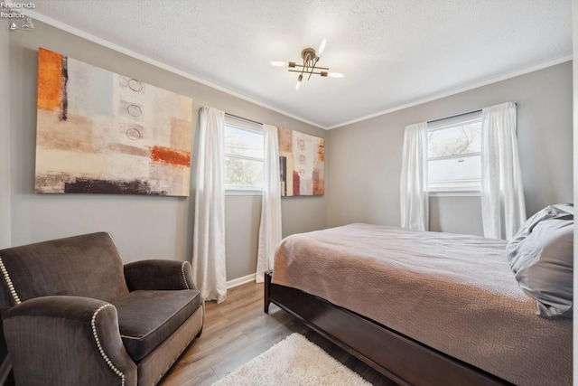 bedroom with ornamental molding, baseboards, light wood finished floors, and a textured ceiling