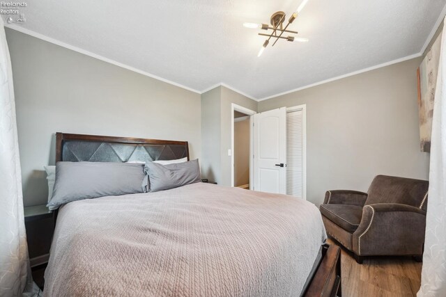 bedroom with a closet, crown molding, and wood finished floors