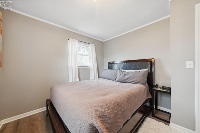bedroom with baseboards, crown molding, and wood finished floors