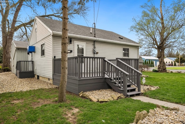 rear view of property with a yard, a shingled roof, and a wooden deck