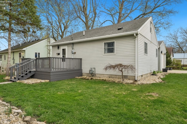 rear view of property with a deck, a lawn, and roof with shingles