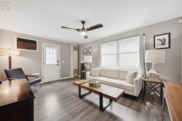 living area featuring ceiling fan, baseboards, wood finished floors, and a wall unit AC