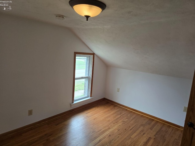 additional living space with baseboards, wood finished floors, and lofted ceiling