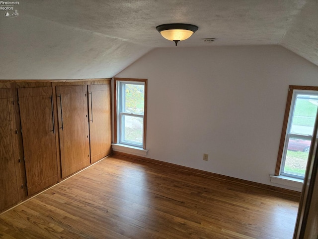 bonus room featuring a textured ceiling, wood finished floors, and lofted ceiling