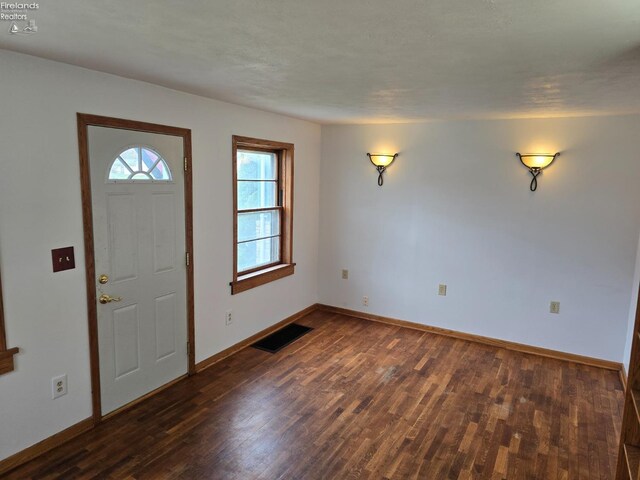 foyer featuring dark wood-type flooring, baseboards, and visible vents