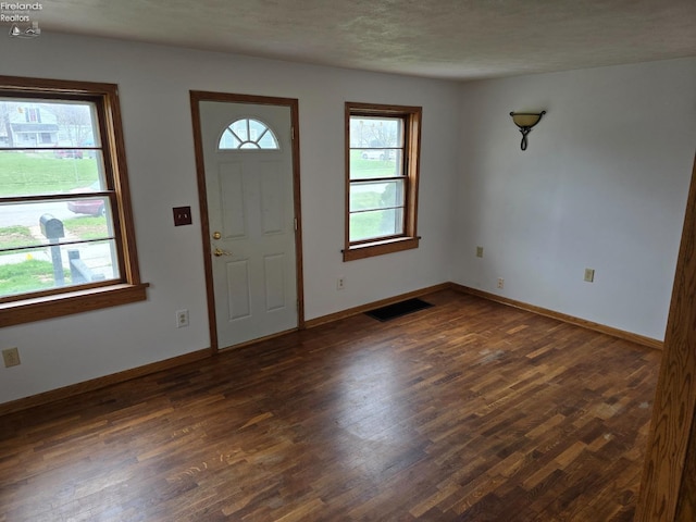 entrance foyer featuring dark wood-style flooring, baseboards, and visible vents