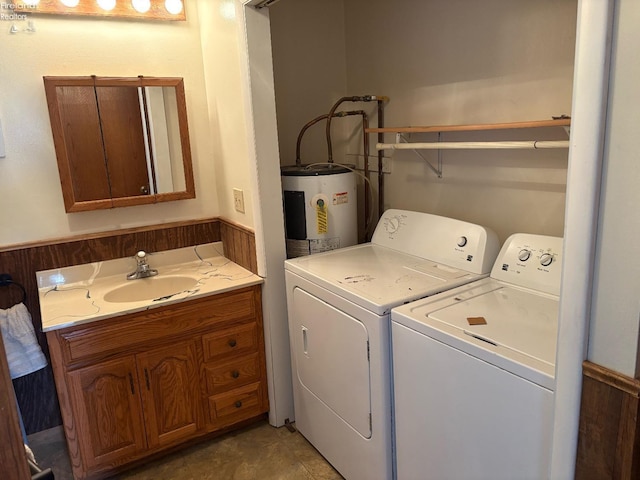 clothes washing area with washing machine and dryer, water heater, a sink, and laundry area