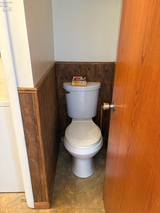 bathroom with a wainscoted wall and toilet