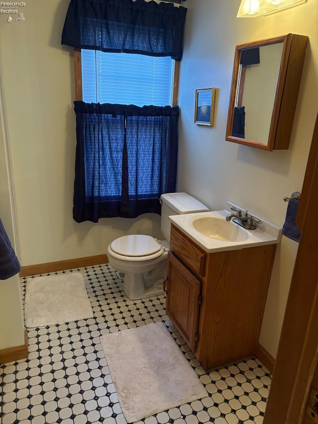 bathroom with baseboards, toilet, and vanity