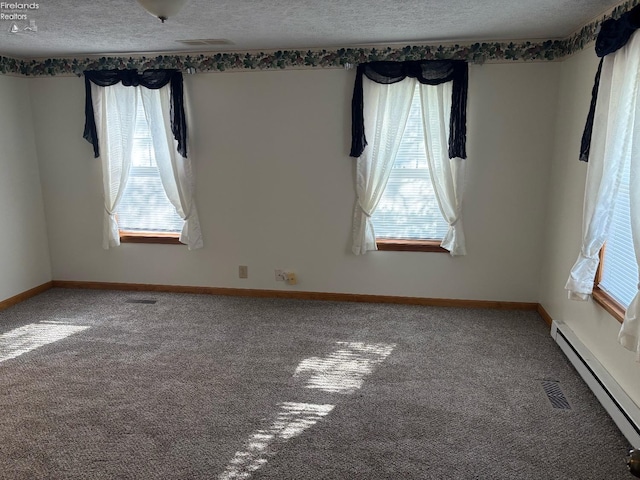 spare room with a baseboard heating unit, plenty of natural light, and carpet