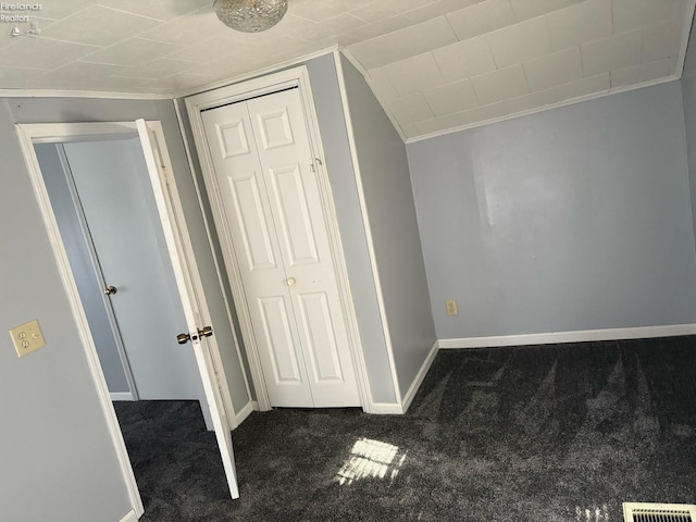 unfurnished bedroom featuring carpet flooring, visible vents, baseboards, a closet, and ornamental molding