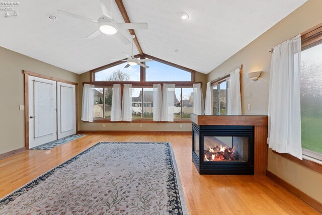 1001 Birchwood Dr, Sandusky, OH 44870 - unfurnished living room with ceiling fan, wood finished floors, a multi sided fireplace, and vaulted ceiling with beams