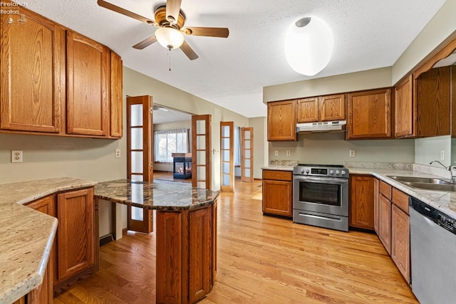 1001 Birchwood Dr, Sandusky, OH 44870 - kitchen featuring brown cabinets, under cabinet range hood, a sink, light wood-style flooring, and appliances with stainless steel finishes