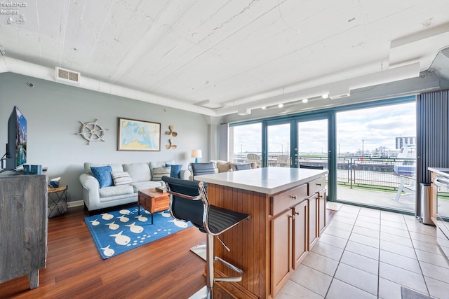 kitchen with a kitchen breakfast bar, brown cabinets, open floor plan, light countertops, and visible vents