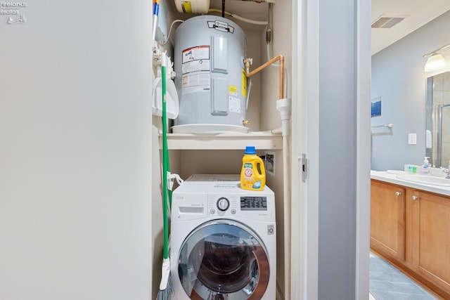 washroom featuring a sink, electric water heater, visible vents, washer / clothes dryer, and laundry area