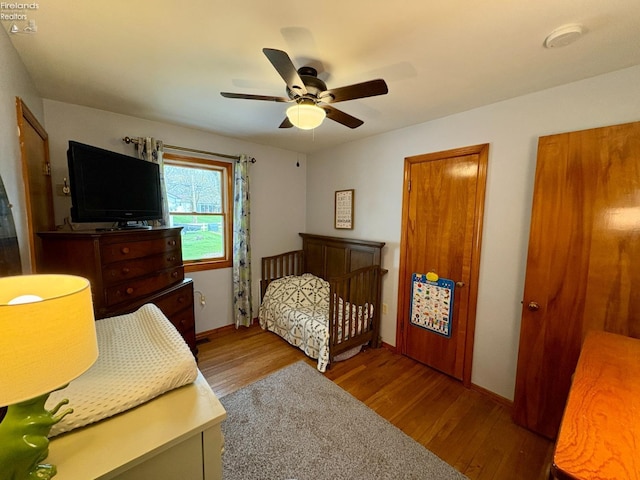 bedroom with wood finished floors, a ceiling fan, and baseboards