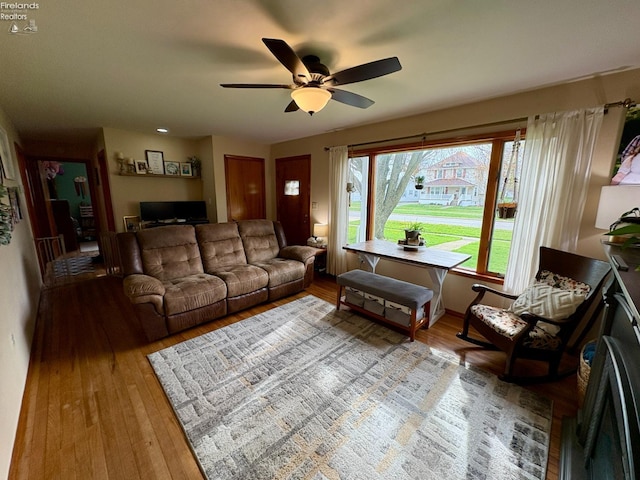 living area featuring light wood-style flooring and a ceiling fan