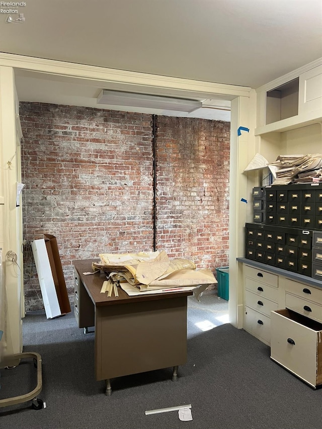 carpeted office space featuring brick wall