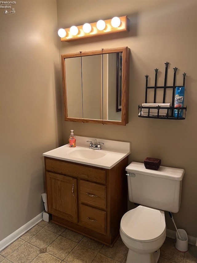 half bath featuring baseboards, toilet, and vanity
