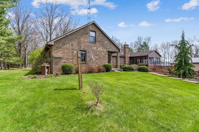 back of property with a wooden deck, a yard, and brick siding