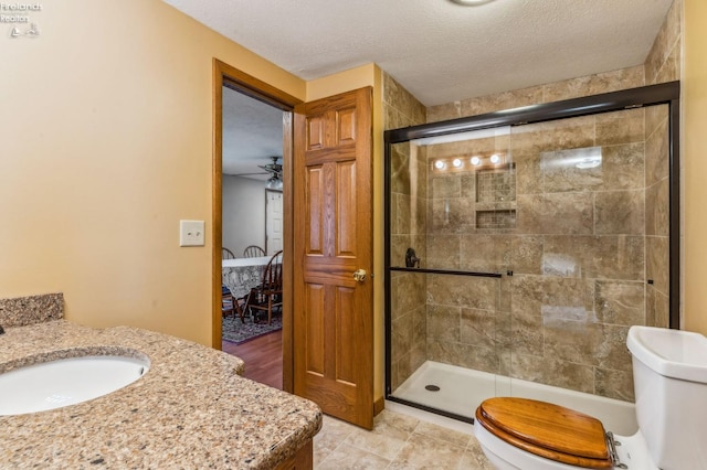 ensuite bathroom featuring a textured ceiling, toilet, and a stall shower