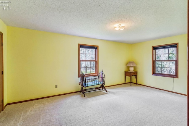 unfurnished room featuring a textured ceiling, baseboards, and light carpet