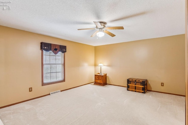carpeted empty room featuring baseboards, a ceiling fan, visible vents, and a textured ceiling