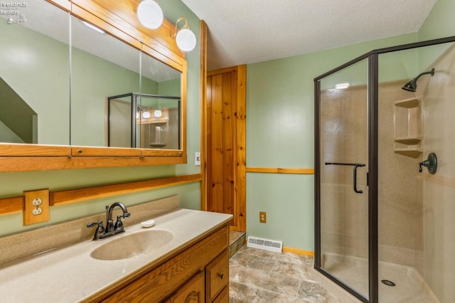 bathroom with a shower stall, vanity, a textured ceiling, and visible vents