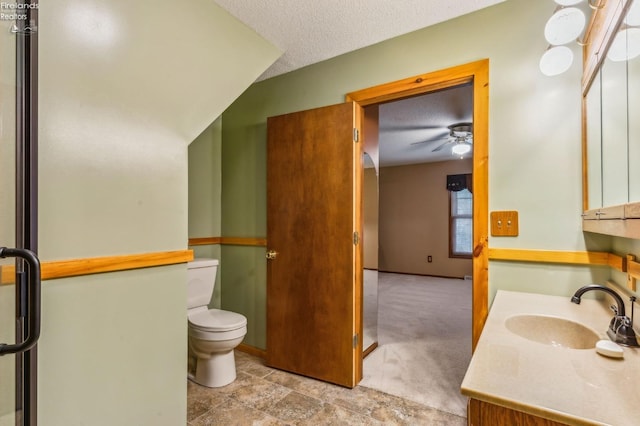 bathroom with toilet, a ceiling fan, vanity, and a textured ceiling