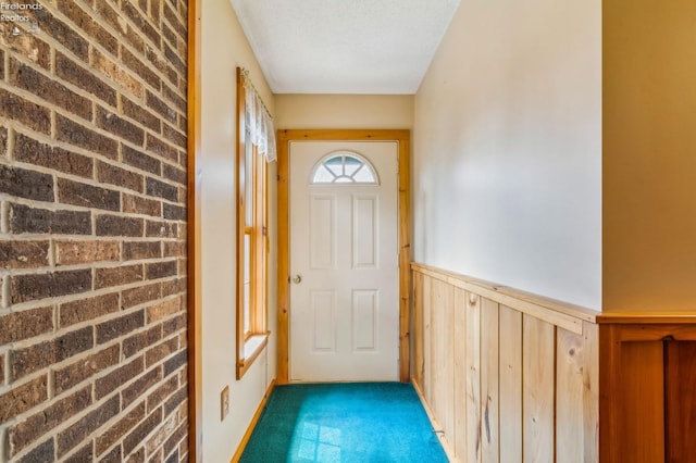 doorway featuring wainscoting and carpet