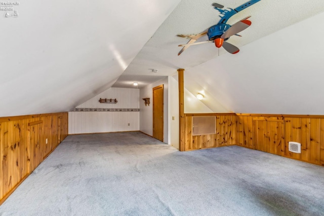bonus room featuring wooden walls, lofted ceiling, and carpet flooring