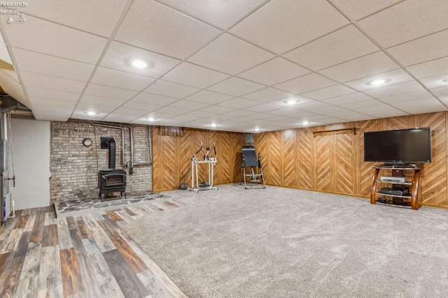 finished below grade area with recessed lighting, carpet, wood walls, wood finished floors, and a wood stove