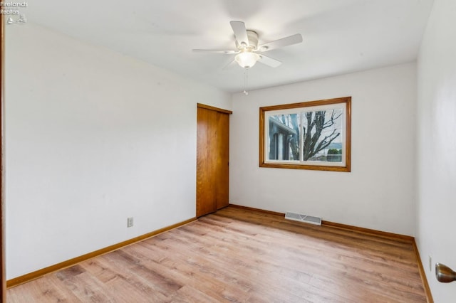 spare room featuring baseboards, a ceiling fan, light wood-style floors, and visible vents