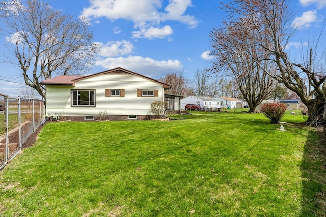 rear view of property with metal roof, a lawn, and fence