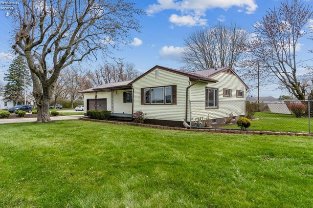 view of front facade with metal roof, concrete driveway, fence, an attached garage, and a front yard