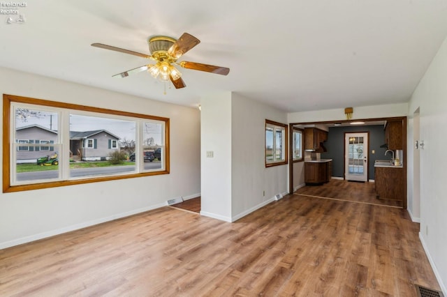 unfurnished living room with wood finished floors, visible vents, and baseboards