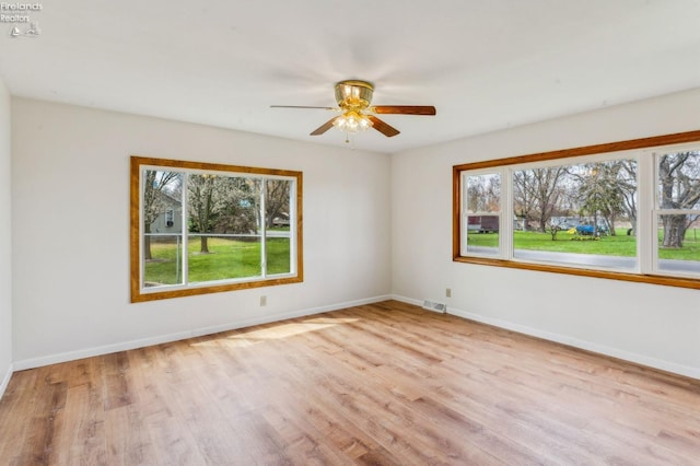 spare room featuring baseboards, wood finished floors, visible vents, and a ceiling fan