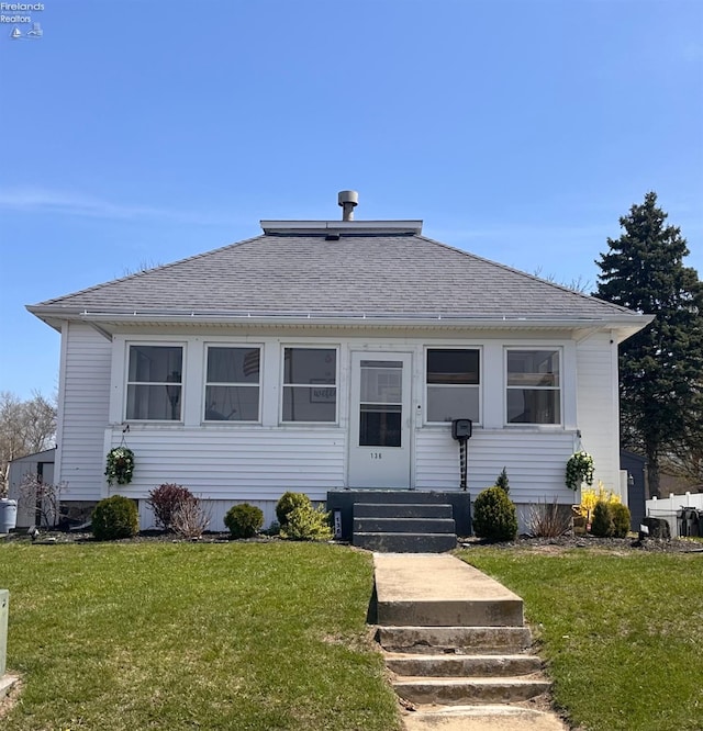 bungalow-style home featuring a shingled roof, a front lawn, and entry steps
