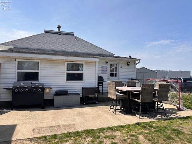 back of house with outdoor dining area, roof with shingles, fence, and a patio area